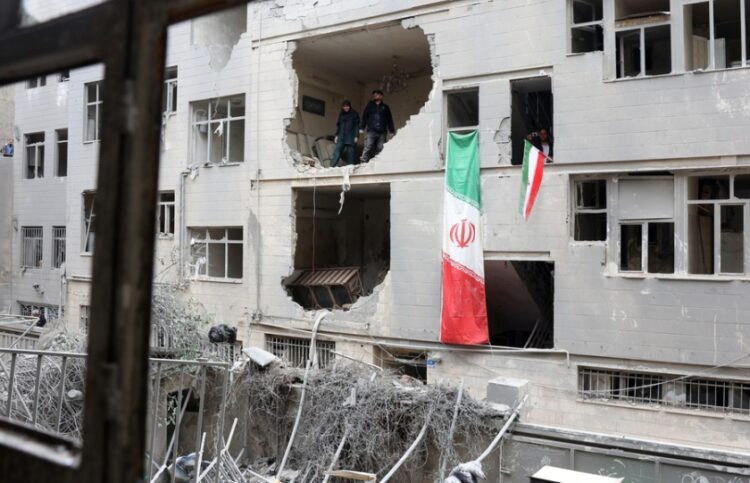 Ιρανοί στέκονται μέσα σε κατεστραμμένο κτήριο κατοικιών στη νότια Τεχεράνη (φωτ.: EPA/Abedin Taherkenareh)