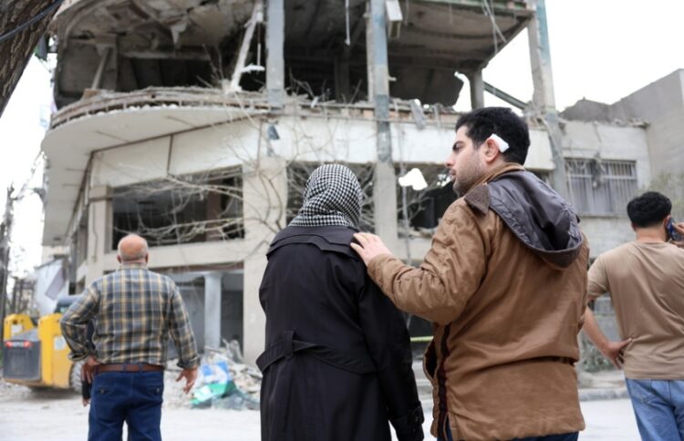 Ιρανοί κοιτούν κατεστραμμένο κτήριο κατοικιών στην Τεχεράνη, μετά από ισραηλινοαμερικανικό πλήγμα (φωτ.: EPA/Abedin Taherkenareh)