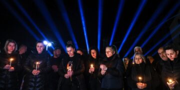 Συγγενείς και φίλοι των θυμάτων κρατούν ένα κερί έξω το νυχτερινό κέντρο όπου σημειώθηκε η φονική πυρκαγιά, ακριβώς έναν χρόνο μετά την τραγωδία (φωτ.: EPA/Georgi Licovski)