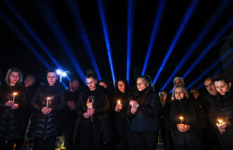 Συγγενείς και φίλοι των θυμάτων κρατούν ένα κερί έξω το νυχτερινό κέντρο όπου σημειώθηκε η φονική πυρκαγιά, ακριβώς έναν χρόνο μετά την τραγωδία (φωτ.: EPA/Georgi Licovski)