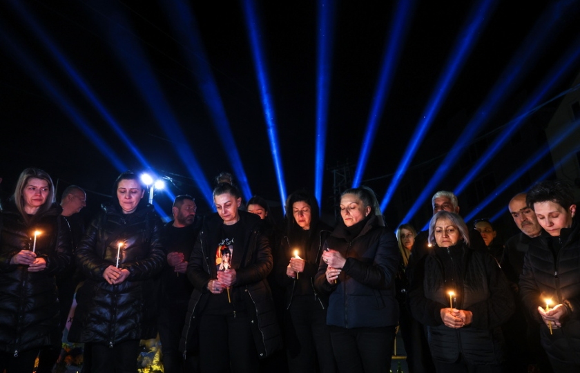 Συγγενείς και φίλοι των θυμάτων κρατούν ένα κερί έξω το νυχτερινό κέντρο όπου σημειώθηκε η φονική πυρκαγιά, ακριβώς έναν χρόνο μετά την τραγωδία (φωτ.: EPA/Georgi Licovski)