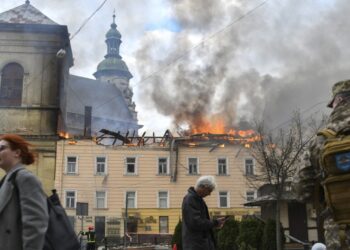 Πεζοί περνούν μπροστά από κτήριο που χτυπήθηκε από ρωσικό drone στον ιστορικό κέντρο της Λβιβ, στη δυτική Ουκρανία (φωτ.: EPA/Mykola Tys)