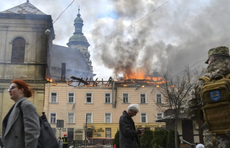 Πεζοί περνούν μπροστά από κτήριο που χτυπήθηκε από ρωσικό drone στον ιστορικό κέντρο της Λβιβ, στη δυτική Ουκρανία (φωτ.: EPA/Mykola Tys)
