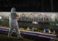 Ουκρανός, ντυμένος με τη στολή των εργαζομένων σε πυρηνικό σταθμό, κρατά κεριά σε τελετή μνήμης για τους «εκκαθαριστές» που έχασαν τη ζωή τους στις επιχειρήσεις καθαρισμού μετά την καταστροφή του Τσερνόμπιλ, στο Σλαβούτιτς της Ουκρανίας (φωτ.: EPA/MAKSYM KISHKA)