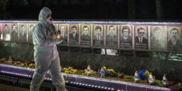 Ουκρανός, ντυμένος με τη στολή των εργαζομένων σε πυρηνικό σταθμό, κρατά κεριά σε τελετή μνήμης για τους «εκκαθαριστές» που έχασαν τη ζωή τους στις επιχειρήσεις καθαρισμού μετά την καταστροφή του Τσερνόμπιλ, στο Σλαβούτιτς της Ουκρανίας (φωτ.: EPA/MAKSYM KISHKA)