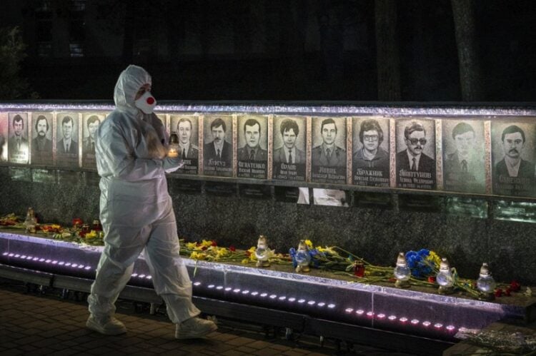 Ουκρανός, ντυμένος με τη στολή των εργαζομένων σε πυρηνικό σταθμό, κρατά κεριά σε τελετή μνήμης για τους «εκκαθαριστές» που έχασαν τη ζωή τους στις επιχειρήσεις καθαρισμού μετά την καταστροφή του Τσερνόμπιλ, στο Σλαβούτιτς της Ουκρανίας (φωτ.: EPA/MAKSYM KISHKA)