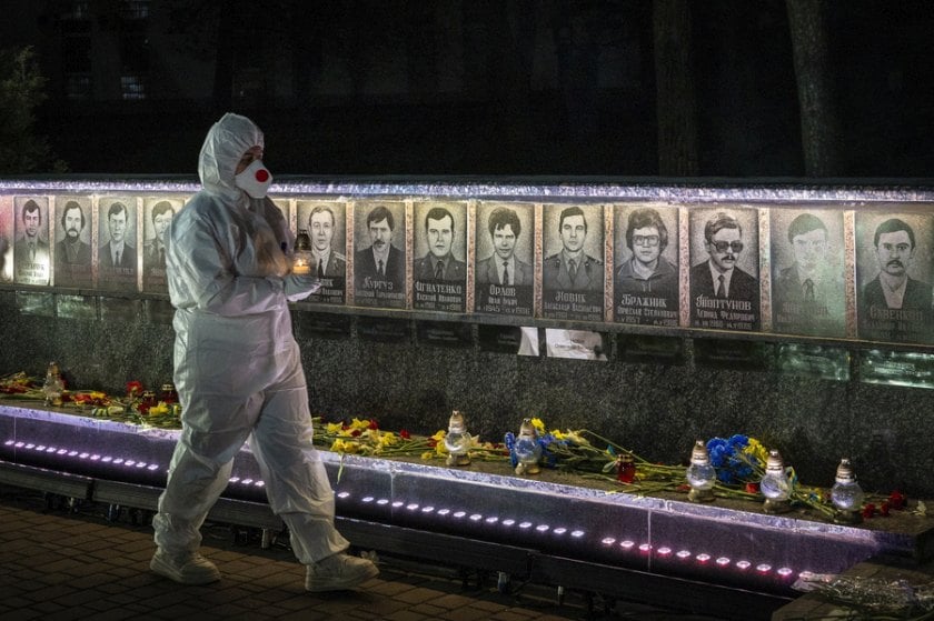 Ουκρανός, ντυμένος με τη στολή των εργαζομένων σε πυρηνικό σταθμό, κρατά κεριά σε τελετή μνήμης για τους «εκκαθαριστές» που έχασαν τη ζωή τους στις επιχειρήσεις καθαρισμού μετά την καταστροφή του Τσερνόμπιλ, στο Σλαβούτιτς της Ουκρανίας (φωτ.: EPA/MAKSYM KISHKA)