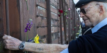 Ο Χάιντς Κούνιο το 2015, 72 χρόνια μετά τη θηριωδία, προτάσσει το χαραγμένο με τον αριθμό 109565 χέρι του μπροστά σε ένα από τα βαγόνια της ατμήλατης μηχανής Λβ 964, μία από αυτές που χρησιμοποιούσαν οι Ναζί για τα ταξίδια θανάτου προς το Άουσβιτς (φωτ.: ΑΠΕ-ΜΠΕ / Νίκος Αρβανιτίδης)