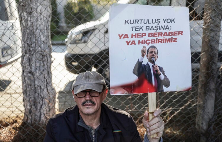 Υποστηρικτής του Ιμάμογλου με πλακάτ που γράφει «Καμία σωτηρία αν είσαι μόνος. Ή όλοι μαζί, ή κανείς» (φωτ.: EPA / Erdem Sahin)