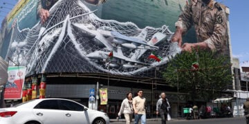 Ιρανοί περνούν μπροστά από γιγαντοαφίσα με το μήνυμα «Τα Στενά του Ορμούζ παραμένουν κλειστά», στην πλατεία Ενγκελάμπ στην Τεχεράνη, 28 Απριλίου 2026 (φωτ.: EPA / Abedin Taherkenareh)