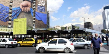 Ιρανός διασχίζει δρόμο μπροστά από γιγαντοαφίσα στην Τεχεράνη, με αναφορά στα Στενά του Ορμούζ και το σύνθημα «Για πάντα στο χέρι του Ιράν». 15 Απριλίου 2026 (φωτ.: EPA / Abedin Taherkenareh)