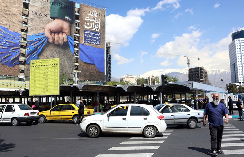 Ιρανός διασχίζει δρόμο μπροστά από γιγαντοαφίσα στην Τεχεράνη, με αναφορά στα Στενά του Ορμούζ και το σύνθημα «Για πάντα στο χέρι του Ιράν». 15 Απριλίου 2026 (φωτ.: EPA / Abedin Taherkenareh)