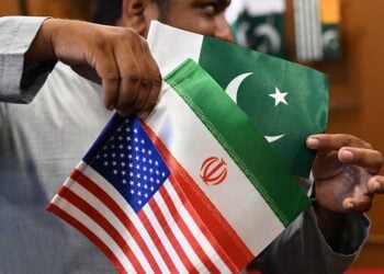 Καταστηματάρχης δείχνει σημαίες του Ιράν, των ΗΠΑ και του Πακιστάν, σε κατάστημα στο Καράτσι (φωτ.: EPA / Shahzaib Akber)