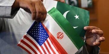 Καταστηματάρχης δείχνει σημαίες του Ιράν, των ΗΠΑ και του Πακιστάν, σε κατάστημα στο Καράτσι (φωτ.: EPA / Shahzaib Akber)