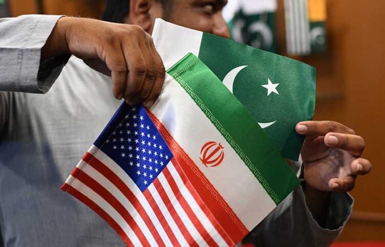 Καταστηματάρχης δείχνει σημαίες του Ιράν, των ΗΠΑ και του Πακιστάν, σε κατάστημα στο Καράτσι (φωτ.: EPA / Shahzaib Akber)