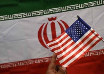 Καταστηματάρχης δείχνει σημαίες του Ιράν και των ΗΠΑ σε κατάστημα στο Καράτσι του Πακιστάν (φωτ.: EPA / Shahzaib Akber)