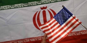 Καταστηματάρχης δείχνει σημαίες του Ιράν και των ΗΠΑ σε κατάστημα στο Καράτσι του Πακιστάν (φωτ.: EPA / Shahzaib Akber)