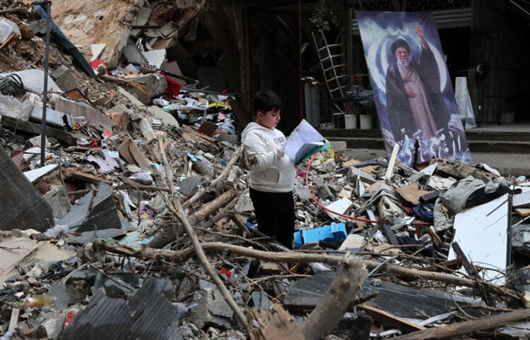 Ένα αγόρι διαβάζει μέσα στα ερείπια βομβαρδισμένου σπιτιού στα προάστια της Βηρυτού, στον Λίβανο. 20 Απριλίου 2026 (φωτ.: EPA / Wael Hamzeh)