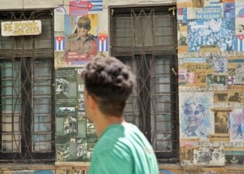 Άνθρωπος περνά μπροστά από ένα σπίτι καλυμμένο με αφίσες στην Αβάνα της Κούβας (φωτ.: EPA/ ERNESTO MASTRASCUSA)