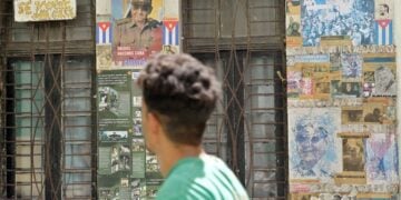 Άνθρωπος περνά μπροστά από ένα σπίτι καλυμμένο με αφίσες στην Αβάνα της Κούβας (φωτ.: EPA/ ERNESTO MASTRASCUSA)