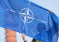 Καναδός στρατιωτικός της Πολυεθνικής Ταξιαρχίας του ΝΑΤΟ κρατά τη σημαία της Συμμαχίας κατά τη διάρκεια στρατιωτικής παρέλασης στο Αϊζκράουκλε της Λετονίας, στις 4 Μαΐου 2026 (φωτ.: EPA / Valda Kalnina)