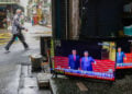 Πεζός περνά μπροστά από κατάστημα επισκευής τηλεοράσεων και μεταχειρισμένων ειδών στην Ταϊπέι, ενώ στις οθόνες μεταδίδεται η συνάντηση του Ντόναλντ Τραμπ με τον Σι Τζινπίνγκ, 14 Μαΐου 2026 (φωτ.: EPA / Ritchie B. Tongo)
