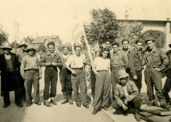 Ο Γιάννης Τζανίδης (κρατά την ελληνική σημαία) με συγκρατούμενούς του στο στρατόπεδο του Άουξμπουργκ τις πρώτες μέρες της απελευθέρωσης, Μάιος 1945 (πηγή: ΓΑΚ Μαγνησίας, Οικογενειακό Αρχείο Κωνσταντίνου Τζανίδη)