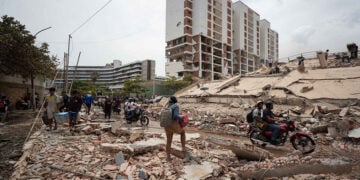 Άνθρωποι περπατούν ανάμεσα στα ερείπια κτηρίων που υπέστησαν ζημιές από τους σεισμούς στη Λα Γκουάιρα της Βενεζουέλας, Παρασκευή 25 Ιουνίου 2026 (φωτ.: EPA / Ronald Pena R)