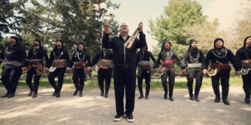 Ο Δημήτρης Καρασαββίδης με χορευτές της Ευξείνου Λέσχης Αθηνών, σε στιγμιότυπο από το βιντεοκλίπ (πηγή: YouTube /
Dimitris Karasavvidis)