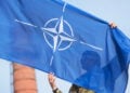 Καναδός στρατιώτης της Πολυεθνικής Ταξιαρχίας του ΝΑΤΟ κρατά τη σημαία της Συμμαχίας κατά τη διάρκεια στρατιωτικής παρέλασης (φωτ.: EPA / Valda Kalnina)