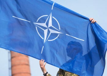 Καναδός στρατιώτης της Πολυεθνικής Ταξιαρχίας του ΝΑΤΟ κρατά τη σημαία της Συμμαχίας κατά τη διάρκεια στρατιωτικής παρέλασης (φωτ.: EPA / Valda Kalnina)