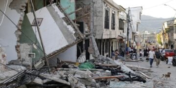 Άνθρωποι περπατούν κοντά στα συντρίμμια ενός σπιτιού στη γειτονιά Κοροσίτο της Περέιρα, στην Κολομβία (φωτ.: EPA/CARLOS ORTEGA)