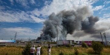 Άνθρωποι παρακολουθούν τον καπνό που υψώνεται πάνω από εγκατάσταση της Wildberries μετά από αναφερόμενη ουκρανική επίθεση με drone στο Βιομηχανικό Πάρκο Κολοντίνο κοντά στο Ποντόλσκ, στην περιφέρεια Μόσχας της Ρωσίας (φωτ.: EPA/STRINGER)