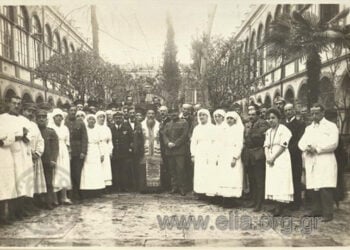 Ο μητροπολίτης Σμύρνης Χρυσόστομος κατά την τελετή των εγκαινίων των ιατρείων του Ερυθρού Σταυρού στο Γραικικό Νοσοκομείο Σμύρνης «Άγιος Χαράλαμπος». Δίπλα του ο πλοίαρχος Η. Μαυρούδης και ο αρχίατρος Β. Τσουνούκας (πηγή: Φωτογραφικό Αρχείο ΕΛΙΑ)