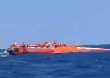 Το αναποδογυρισμένο καταμαράν ανοιχτά της κατεχόμενης Κερύνειας, με επιβαίνοντες να περιμένουν τη διάσωσή τους πάνω στο εκτεθειμένο τμήμα του σκάφους (φωτ.: Takvim / στιγμιότυπο από βίντεο)