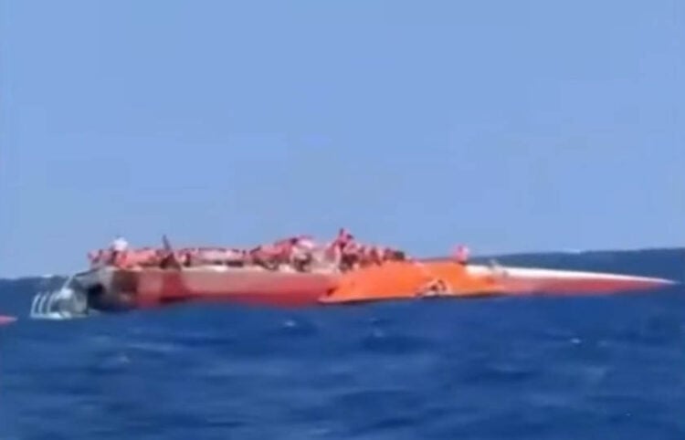 Το αναποδογυρισμένο καταμαράν ανοιχτά της κατεχόμενης Κερύνειας, με επιβαίνοντες να περιμένουν τη διάσωσή τους πάνω στο εκτεθειμένο τμήμα του σκάφους (φωτ.: Takvim / στιγμιότυπο από βίντεο)