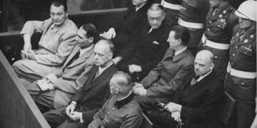 Κατηγορούμενοι στο εδώλιο της Δίκης της Νυρεμβέργης, το 1945–1946. Στην πρώτη σειρά, από αριστερά, ο Χέρμαν Γκέρινγκ, ο Ρούντολφ Ες, ο Γιόαχιμ φον Ρίμπεντροπ και ο Βίλχελμ Κάιτελ (φωτ.: NARA / U.S. Army)