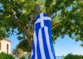 Το Μνημείο της Μικρασιάτισσας Μάνας στη Νέα Κούταλη, καλυμμένο με την ελληνική σημαία μετά την επιμνημόσυνη δέηση και την κατάθεση στεφάνων (φωτ.: Facebook / Κοινότητα Νέας Κούταλης Λήμνου)