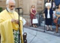 Ο π. Αθανάσιος Γιουσμάς κρατά στα χέρια του το σταυρό (φωτ.: «Νέα της Λέσβου»)