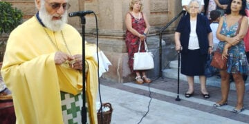 Ο π. Αθανάσιος Γιουσμάς κρατά στα χέρια του το σταυρό (φωτ.: «Νέα της Λέσβου»)