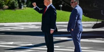 Ο Αμερικανός πρόεδρος Ντόναλντ Τραμπ (αριστερά) χαιρετά με υψωμένη τη γροθιά το πλήθος πίσω από το σχοινί ασφαλείας, κατά την αναχώρησή του από τον Λευκό Οίκο στην Ουάσινγκτον (φωτ.:  EPA/ANNABELLE GORDON / POOL)