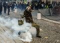 Διαδηλωτής κλωτσάει δακρυγόνο κατά τη διάρκεια συγκρούσεων με την αστυνομία σε διαμαρτυρία ενάντια στο αυξανόμενο κόστος διαβίωσης και τις περικοπές στις δημόσιες υπηρεσίες στο Παρίσι, Γαλλία (φωτ.: EPA/ MOHAMMED BADRA)
