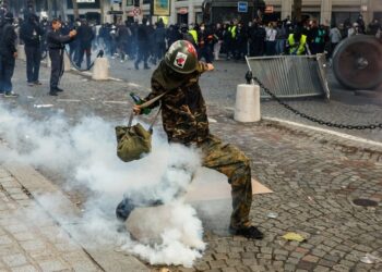 Διαδηλωτής κλωτσάει δακρυγόνο κατά τη διάρκεια συγκρούσεων με την αστυνομία σε διαμαρτυρία ενάντια στο αυξανόμενο κόστος διαβίωσης και τις περικοπές στις δημόσιες υπηρεσίες στο Παρίσι, Γαλλία (φωτ.: EPA/ MOHAMMED BADRA)