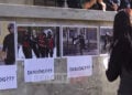 Διαδηλώτρια τοιχοκολλάει φωτογραφίες έξω από το γραφείο του Έντι Ράμα. Η λέξη «διάλογος» συνοδεύει τα αποδεικτικά στοιχεία για την αστυνομική βία. Τρίτη 20 Οκτωβρίου 2026 (πηγή: YouTube / Report TV)