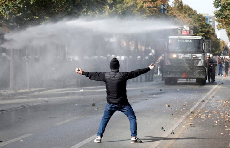 Διαδηλωτής με πέτρες στα χέρια απέναντι από «Αύρα», κατά τη διάρκεια φοιτητικής διαδήλωσης στα Τίρανα, στις 15 Οκτωβρίου 2026 (φωτ.: EPA / Malton Dibra)