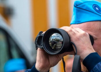Στέλεχος της Frontex με μονόκυαλο στα Σκόπια, πριν από την τελετή έναρξης της κοινής επιχείρησης, στις 20 Απριλίου 2023 (φωτ.: EPA / Georgi Licovski)