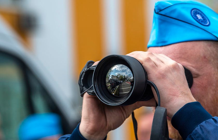 Στέλεχος της Frontex με μονόκυαλο στα Σκόπια, πριν από την τελετή έναρξης της κοινής επιχείρησης, στις 20 Απριλίου 2023 (φωτ.: EPA / Georgi Licovski)