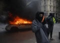 Διαδηλωτές ποζάρουν μπροστά σε φλεγόμενο αυτοκίνητο στο Παρίσι, στη διάρκεια διαδήλωσης κατά της ακρίβειας και των περικοπών στις δημόσιες υπηρεσίες, στις 17 Οκτωβρίου 2026 (φωτ.: EPA / Mohammed Badra)