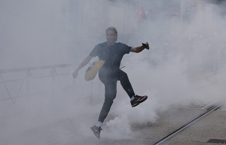 Μαθητής λυκείου κλωτσά κάνιστρο δακρυγόνου κατά τη διάρκεια συγκρούσεων με αστυνομικές δυνάμεις, σε διαδήλωση για τις συνθήκες στην εκπαίδευση στο Μονπελιέ της νότιας Γαλλίας, στις 2 Οκτωβρίου 2026 (φωτ.: EPA / Guillaume Horcajuelo)