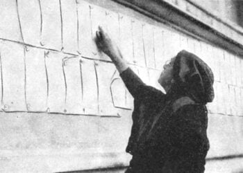 Γυναίκα εξετάζει καταλόγους με ονόματα ανθρώπων που αναζητούσαν οι συγγενείς τους, στα παλιά βασιλικά ανάκτορα της Αθήνας, όπου στεγάζονταν γραφεία της Near East Relief (φωτ.: Near East Relief Historical Society)